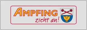 Schild mit dem Text „Ampfing zieht an!“ in kräftigen roten und gelben Buchstaben. Rechts befindet sich ein Wappen mit zwei gekreuzten Keulen und einer Krone. Das Schild hat einen grauen Rand.